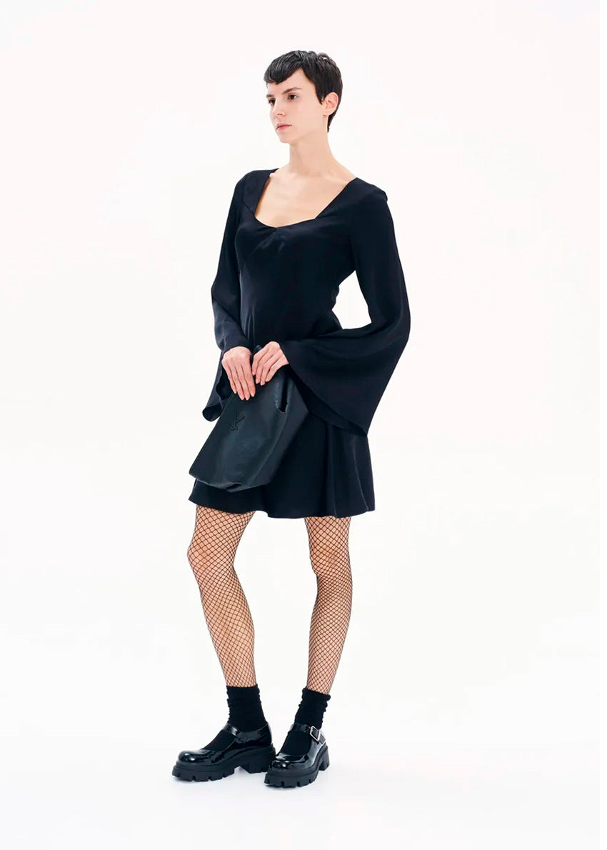 A model wearing a black mini dress with long bell sleeves and a V-neckline, standing against a white background.