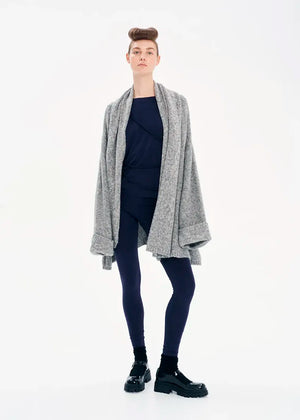 A model wearing a gray knit cardigan with long sleeves and a non-detachable scarf, paired with dark pants and black boots.