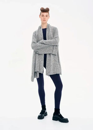 A model wearing a gray knit cardigan with long sleeves and a non-detachable scarf, paired with dark pants and black boots.