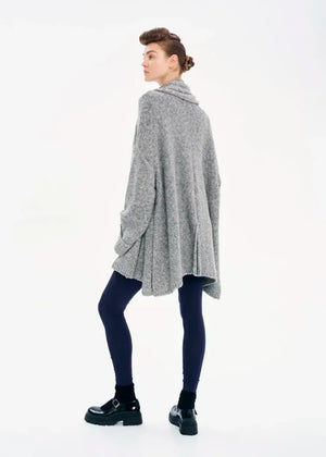A model wearing a gray knit cardigan with long sleeves and a non-detachable scarf, paired with dark pants and black boots.