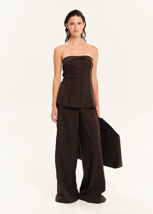 Woman wearing a black strapless top and wide-leg pants on a white background