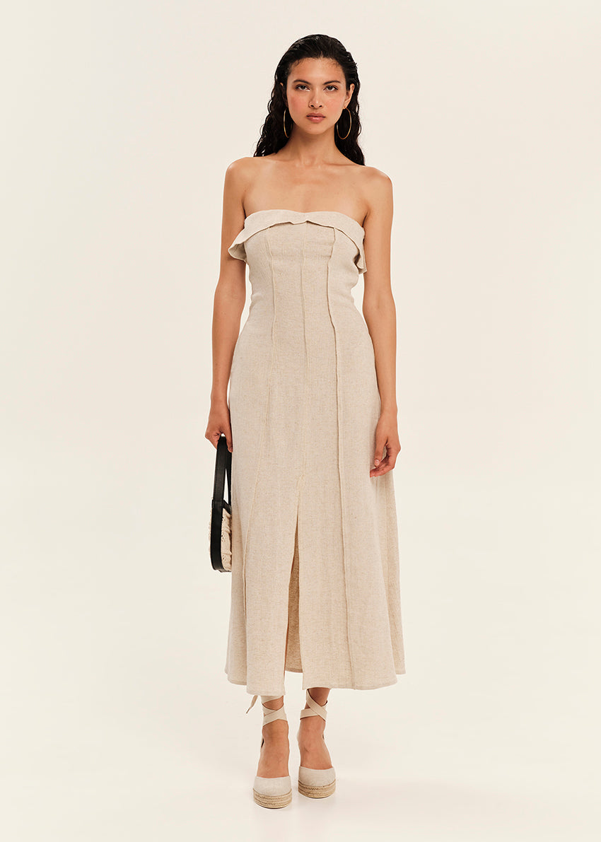 Woman wearing a beige strapless dress on a plain background