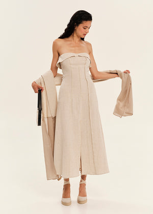 Woman wearing a beige strapless dress holding a matching scarf on a white background