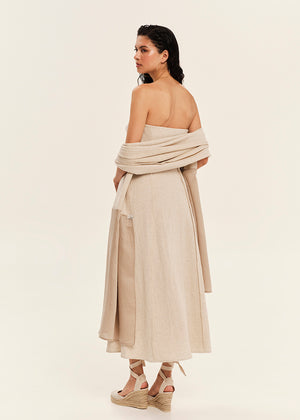 Woman wearing a beige strapless dress with a draped design on a plain background