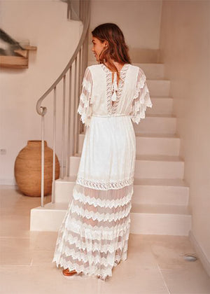 Woman in a white lace dress standing on a staircase in a home setting