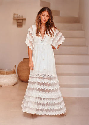 Woman wearing a white lace dress standing on a staircase.