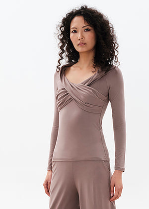 A woman wearing a gray longsleeve cross-over top with a V-neckline, made of eco-friendly viscose.