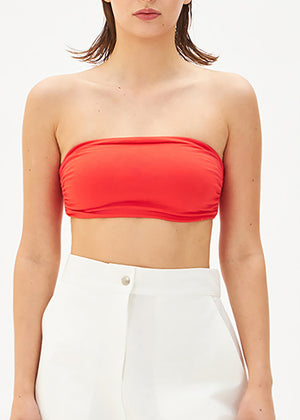 A person wearing a red bustier top with white pants