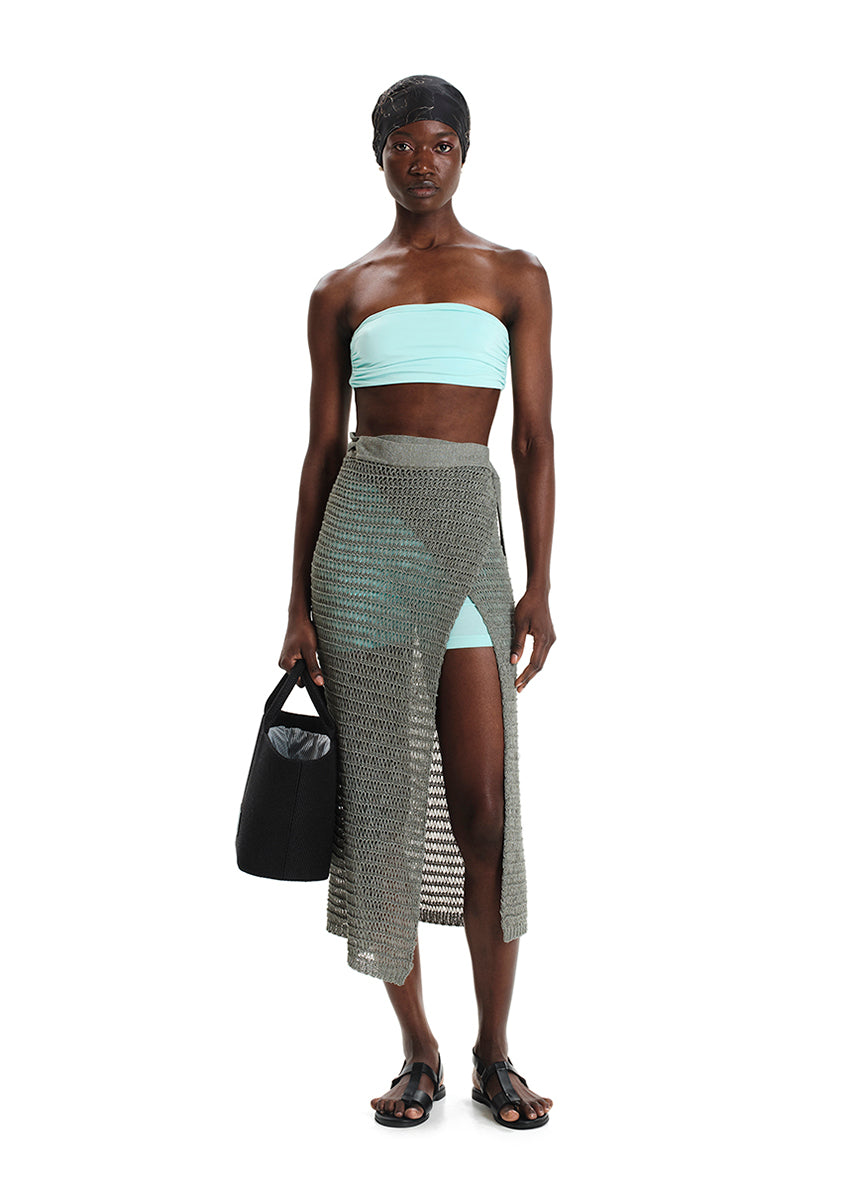 A model wearing a strapless bandeau top in mint color, paired with a long, striped skirt. 