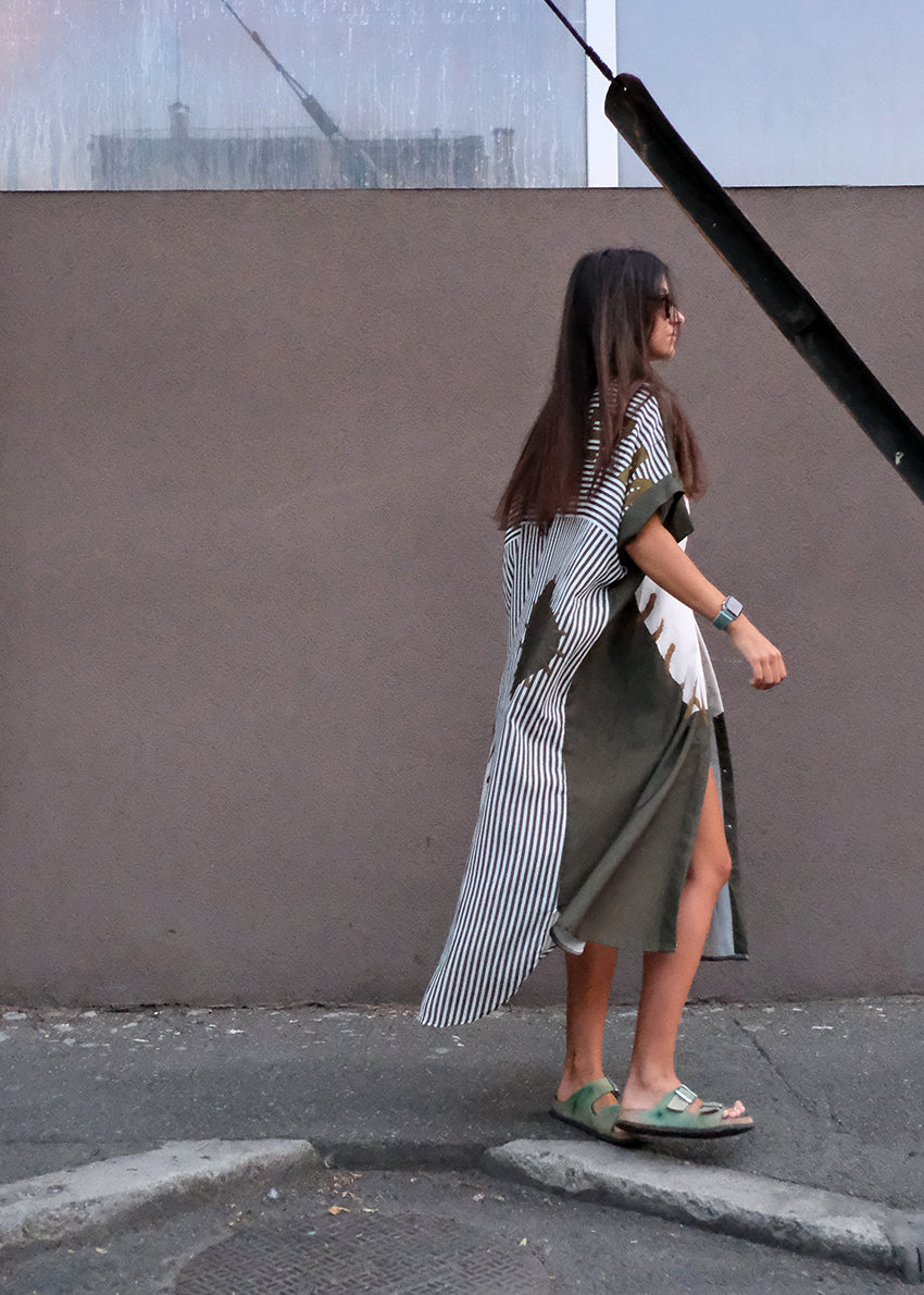 Woman walking on a sidewalk wearing a long striped shirt