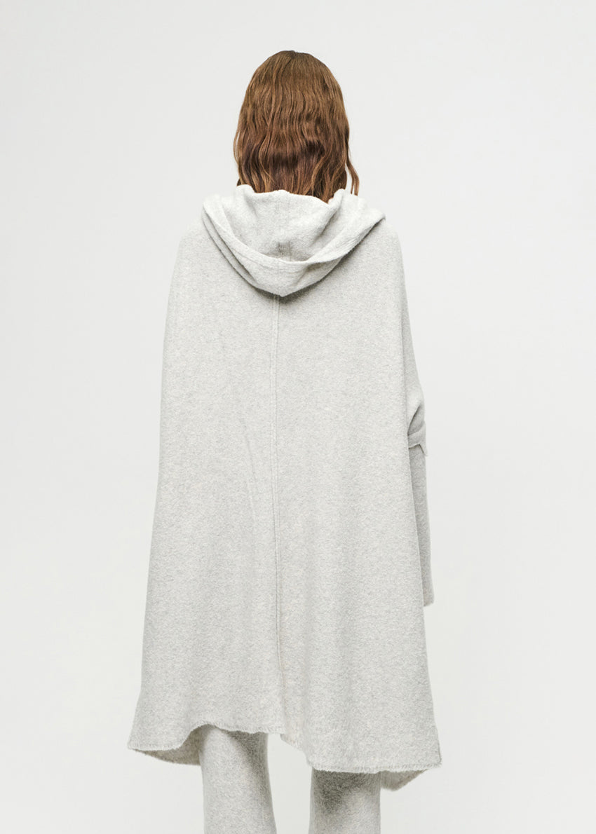 Person wearing a light gray hooded cardigan on a white background