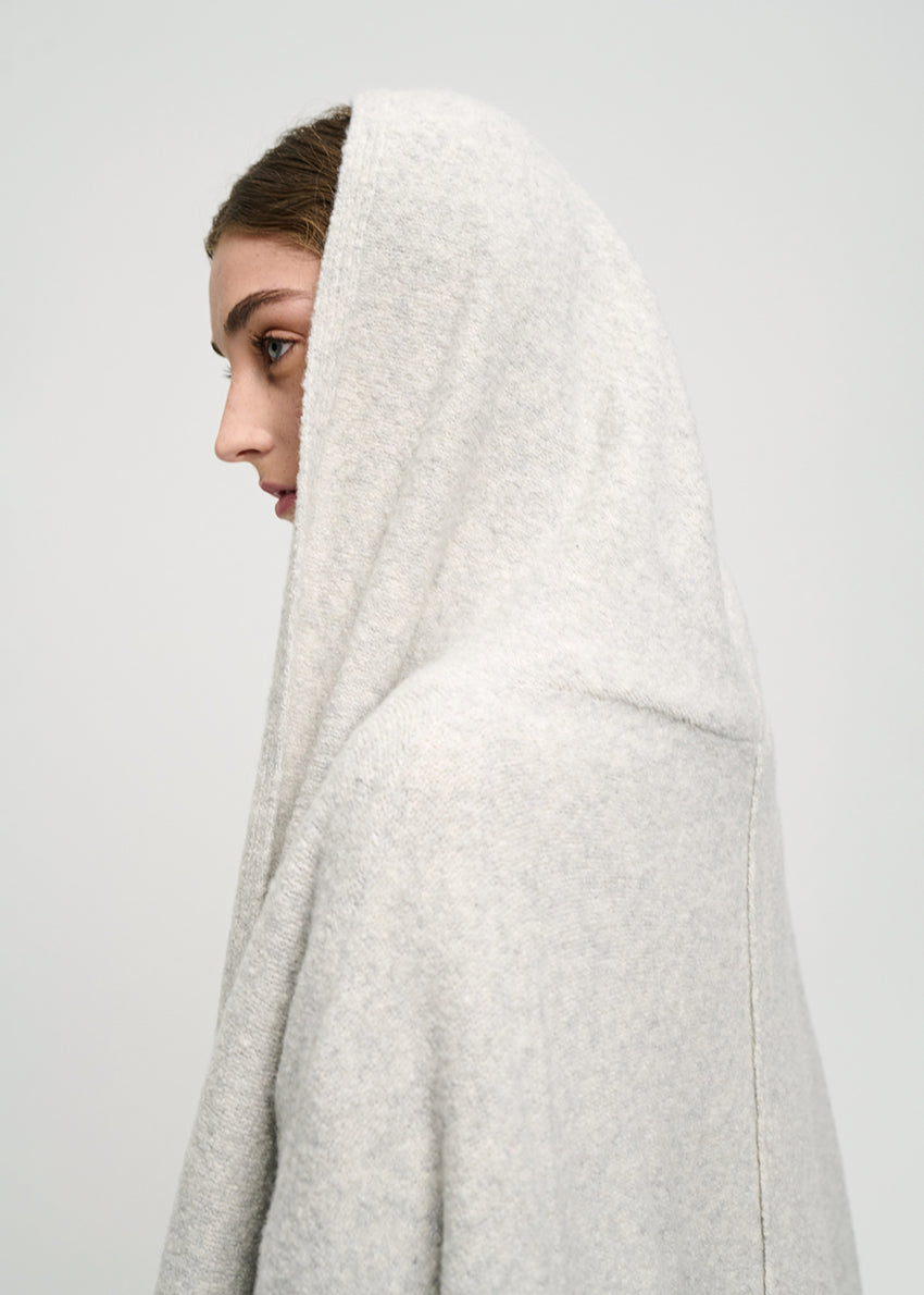 Person wearing a long grey cardigan on a white background