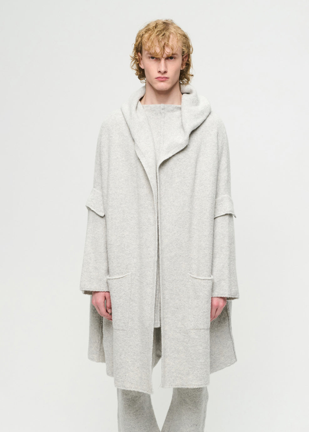 Person wearing a light grey cardigan on a white background