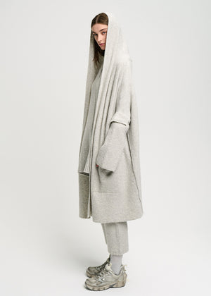 Person wearing a long grey cardigan on a white background