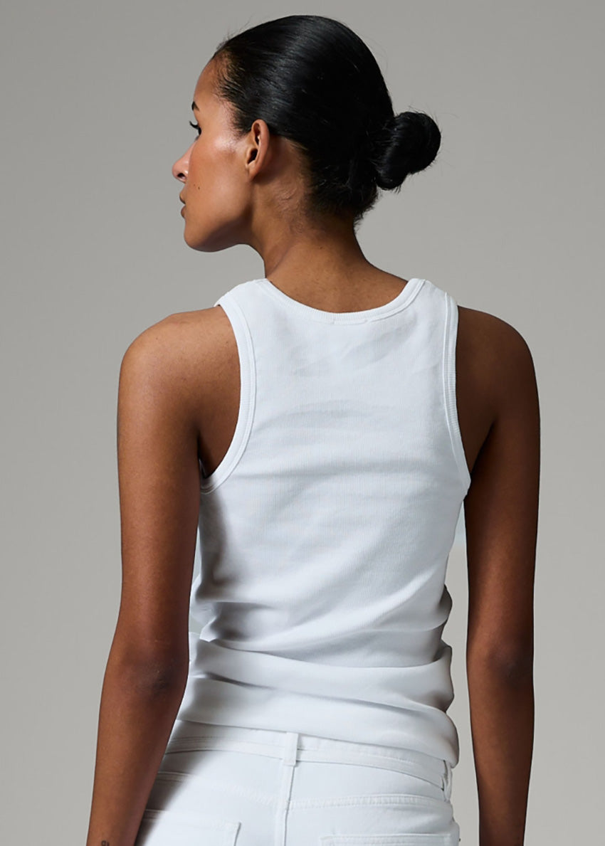 Woman wearing a white sleeveless top against a gray background