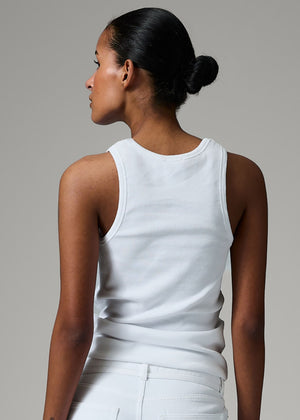 Woman wearing a white sleeveless top against a gray background