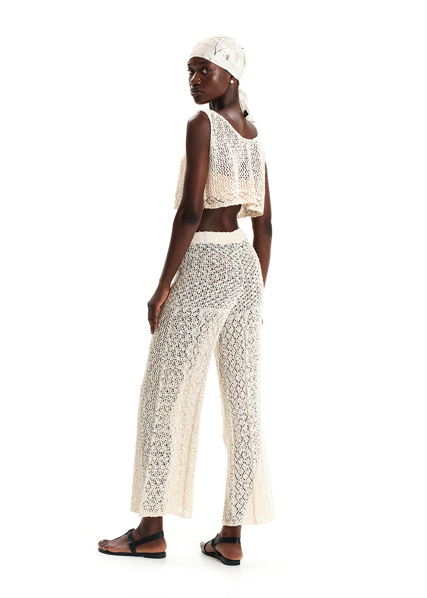 Woman wearing a beige crochet top and skirt set on a white background