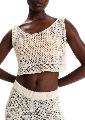 Woman wearing a beige crochet top and skirt set on a white background