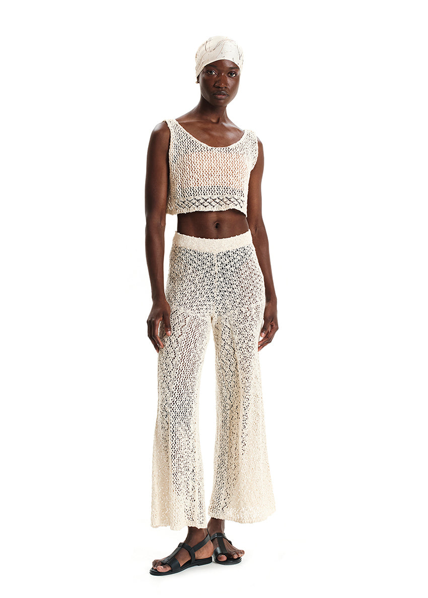 Woman wearing a white crochet outfit on a white background