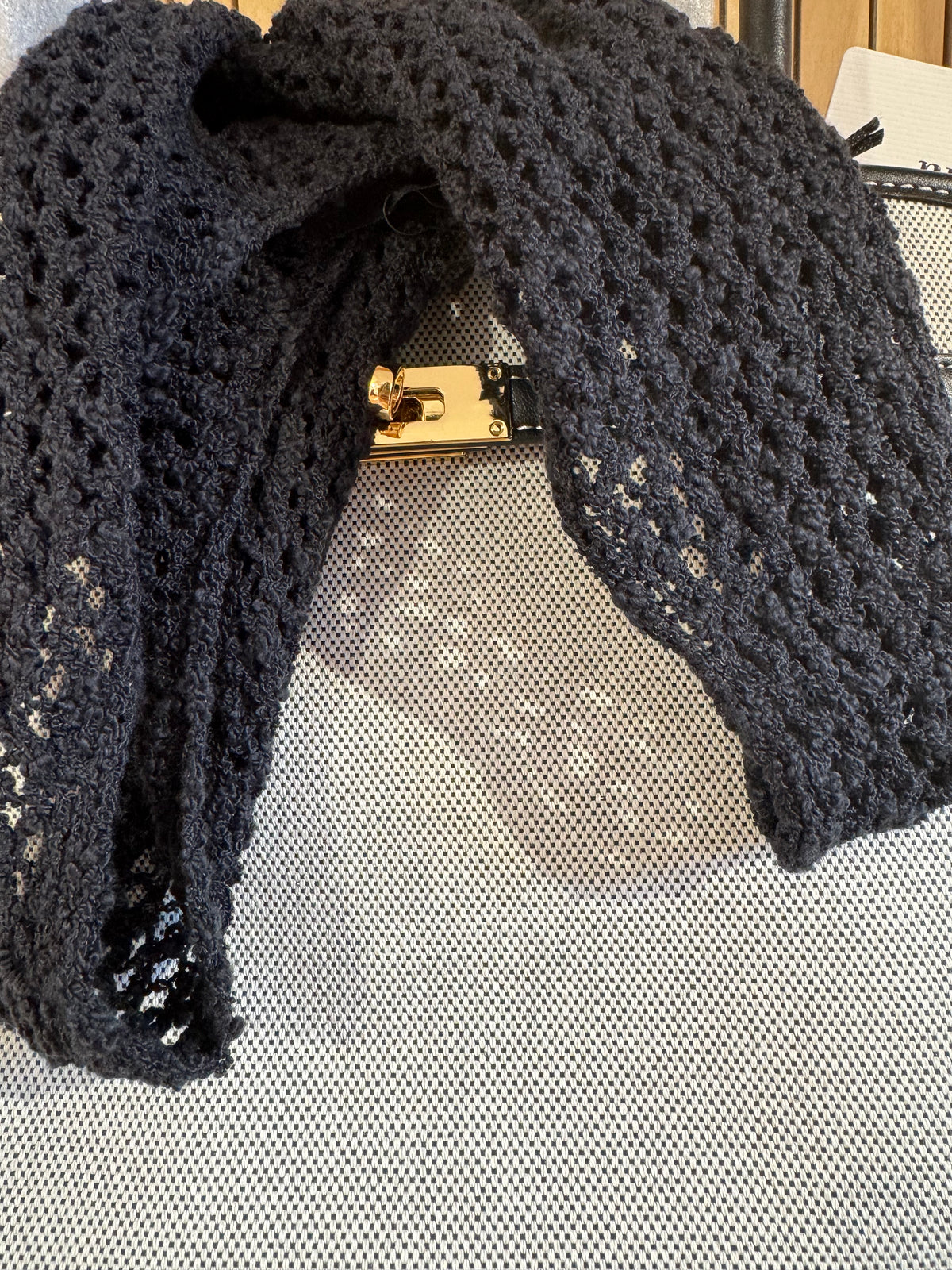 Black lace gloves with a gold clasp on a textured surface