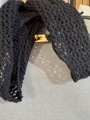 Black lace gloves with a gold clasp on a textured surface