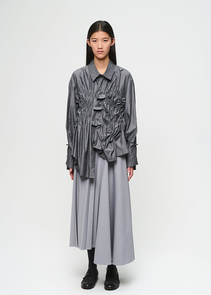 Person wearing a layered outfit with a striped shirt and long skirt on a white background