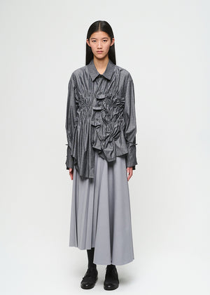 Person wearing a layered outfit with a striped shirt and long skirt on a white background