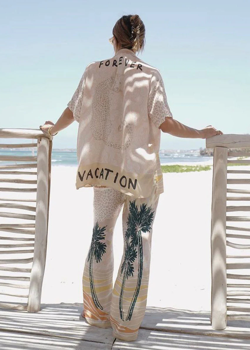 Person wearing a shirt with 'FOREVER VACATION' text on a beach setting
