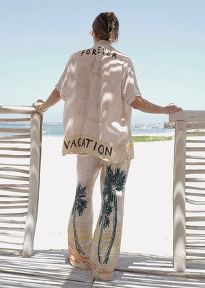 Person wearing a shirt with 'FOREVER VACATION' text on a beach setting