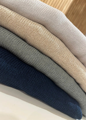 Stack of folded fabric swatches in blue, green, beige, and white.