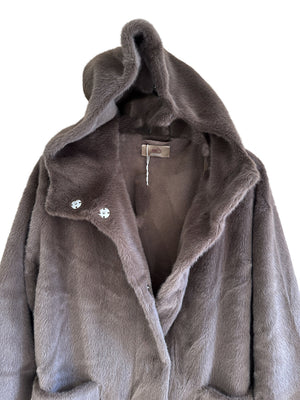 This ultra-fine faux-fur coat features a high density weave of fibres that are thinner than silk, providing a soft and fluffy texture. The coat is fully lined and includes a hoodie, plank frontal pockets, and metallic staples, all in a solid color. 
