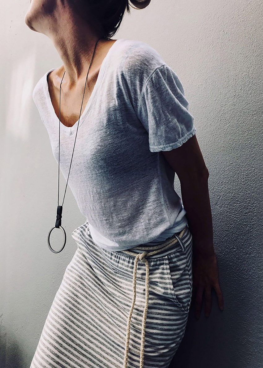 Person wearing a white gray t-shirt and striped skirt against a plain wall.