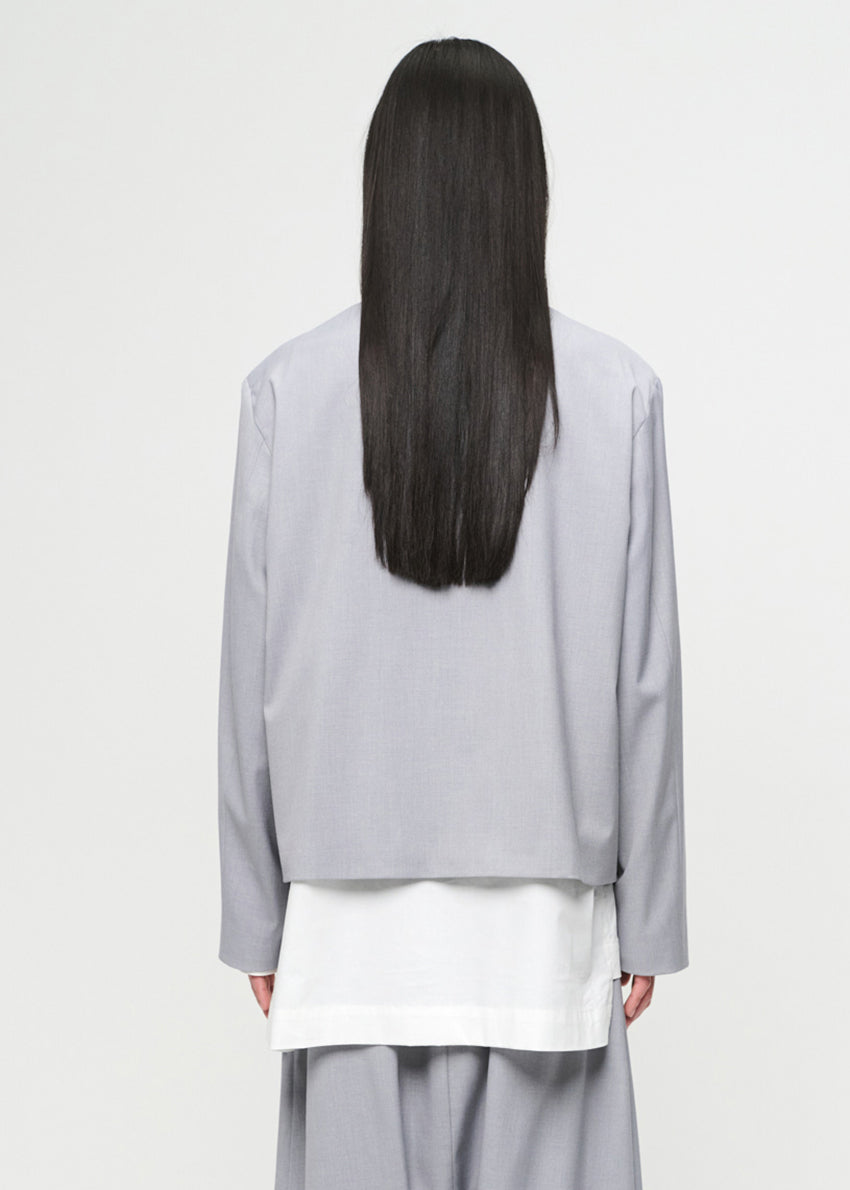 Person wearing a light gray outfit with long dark hair on a white background