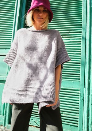 Woman wear a pink hat with a grey poncho and black pants