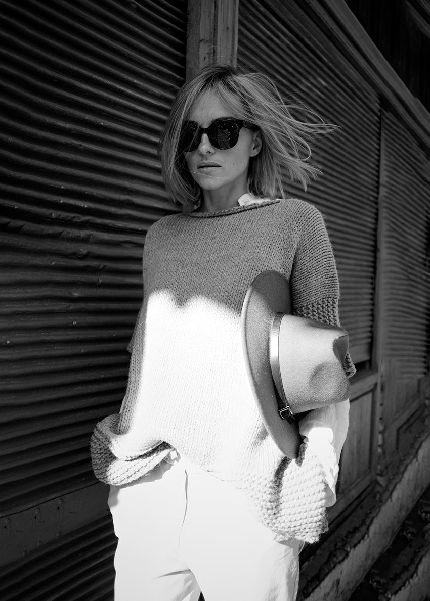 Woman wearing a grey poncho with hat and sunglasses 