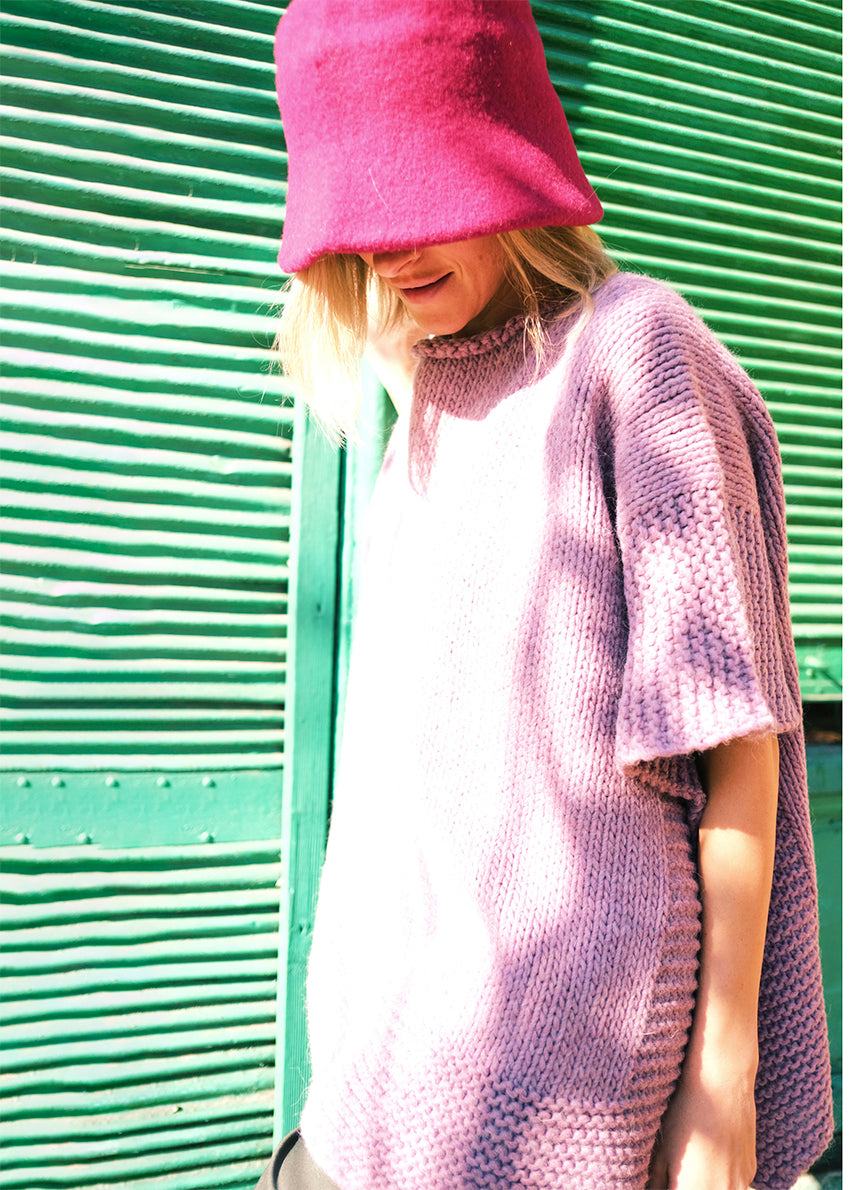 Woman wearing a deep pink hat a thistle poncho