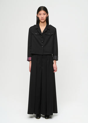 Person wearing a black outfit with a jacket and long skirt on a white background