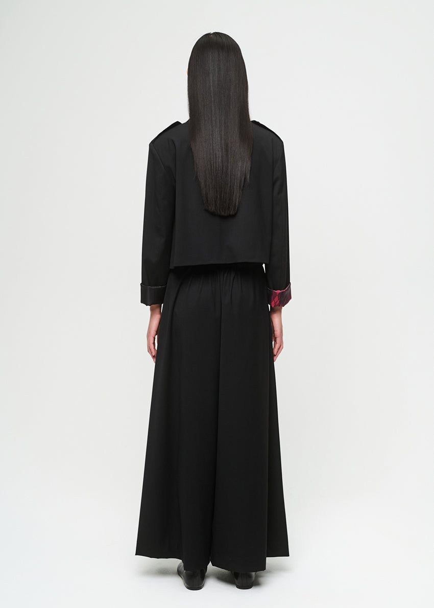 Person wearing a black outfit with a long skirt on a white background