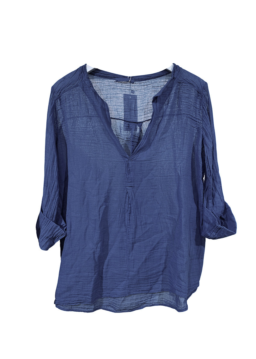 A woman wearing a blue, long-sleeved, oversized shirt with buttons, paired with jeans and a belt.