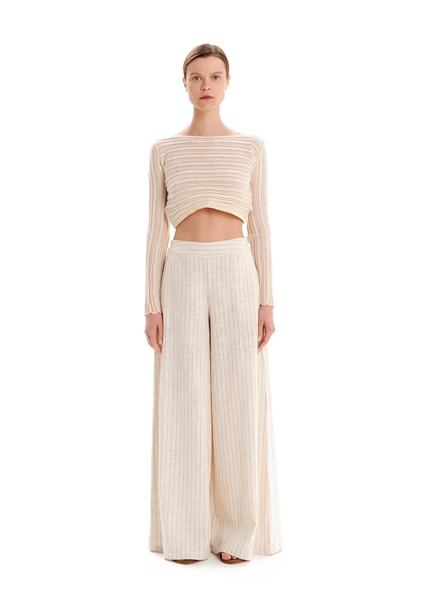 Person wearing a beige knit crop top with matching pants on a white background 