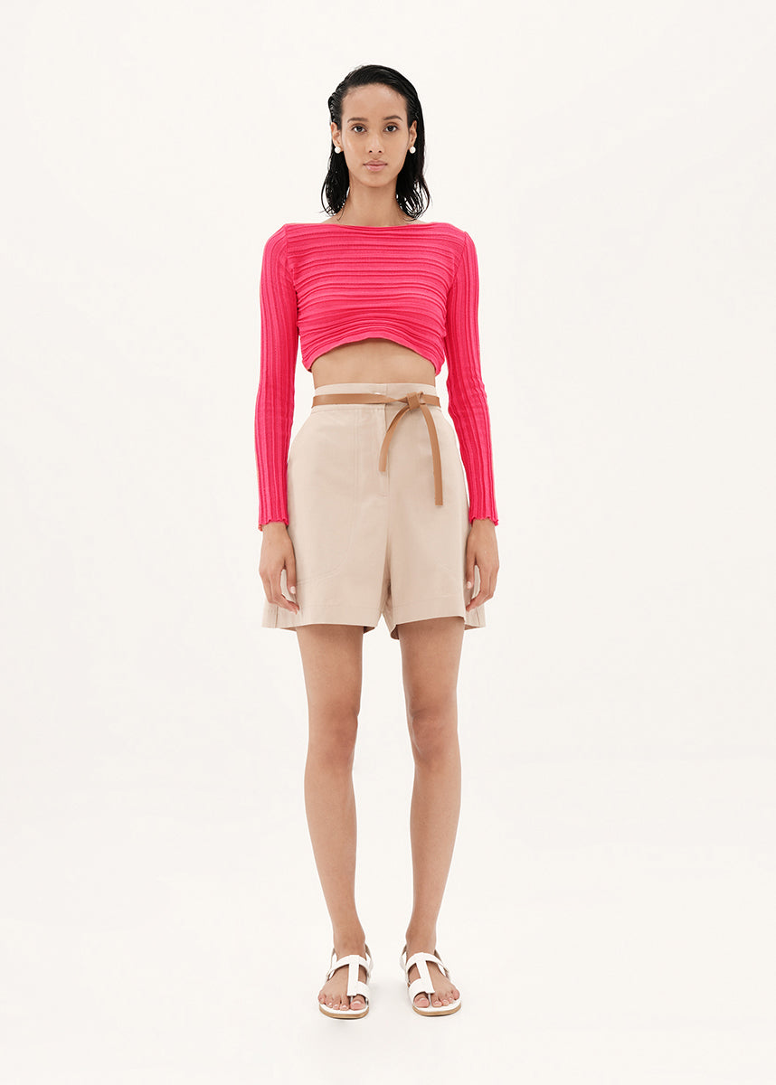 Woman wearing a pink top and beige shorts on a white background