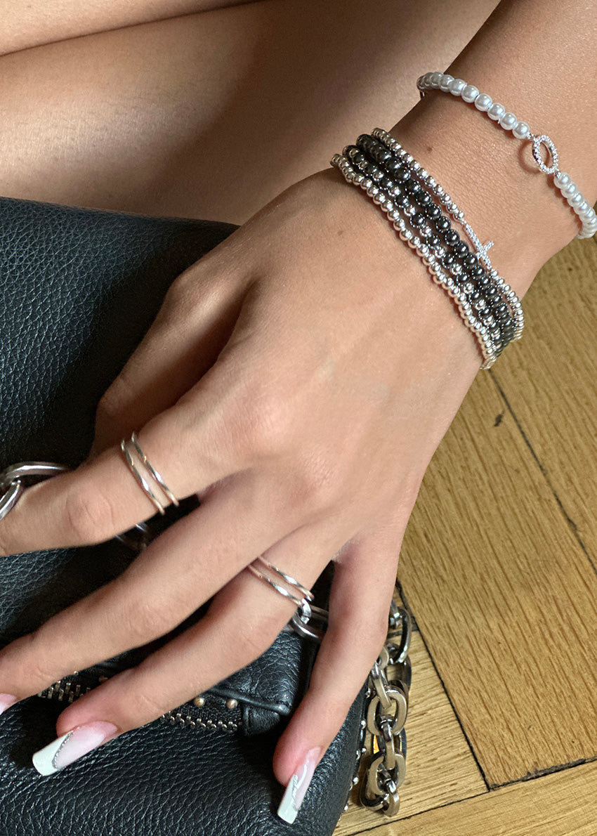 Adjustable corded bracelet with silver plating and cubic zirconia beads, with a loop closure.