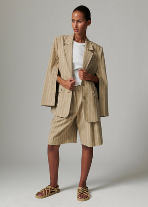 Woman wearing a beige suit with shorts on a plain background