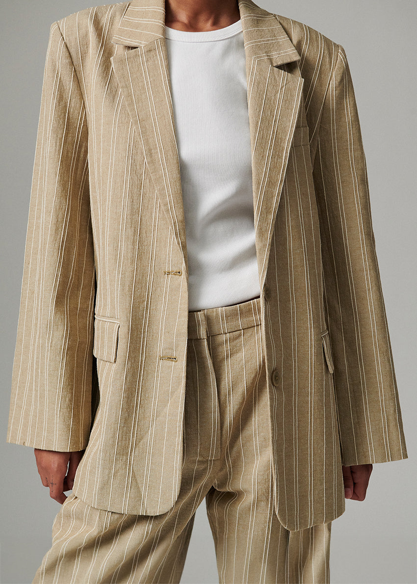 Beige pinstripe suit with white shirt on a gray background