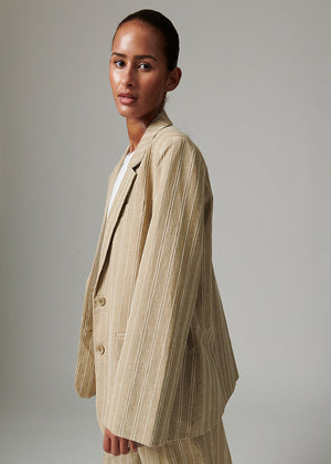 Woman wearing a beige pinstripe suit against a plain background