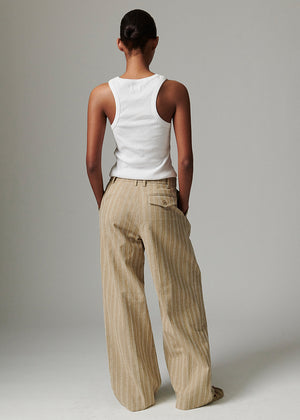 Person wearing a white tank top and beige striped pants on a plain background