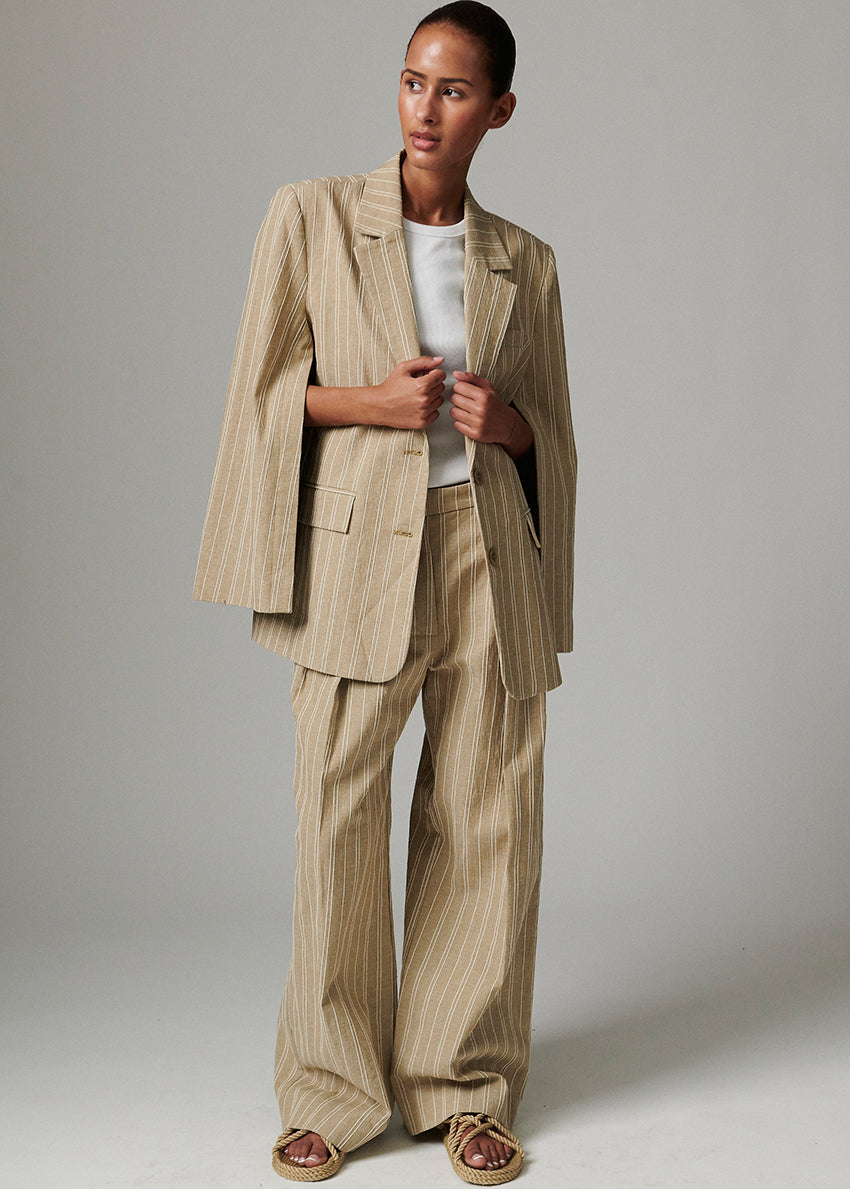 Woman wearing a beige striped suit against a plain background