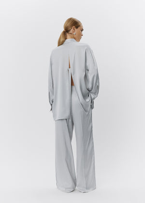 Woman wearing a light gray outfit with a cutout design on a white background