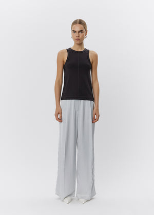 Woman wearing a black sleeveless top and light gray wide-leg pants on a white background