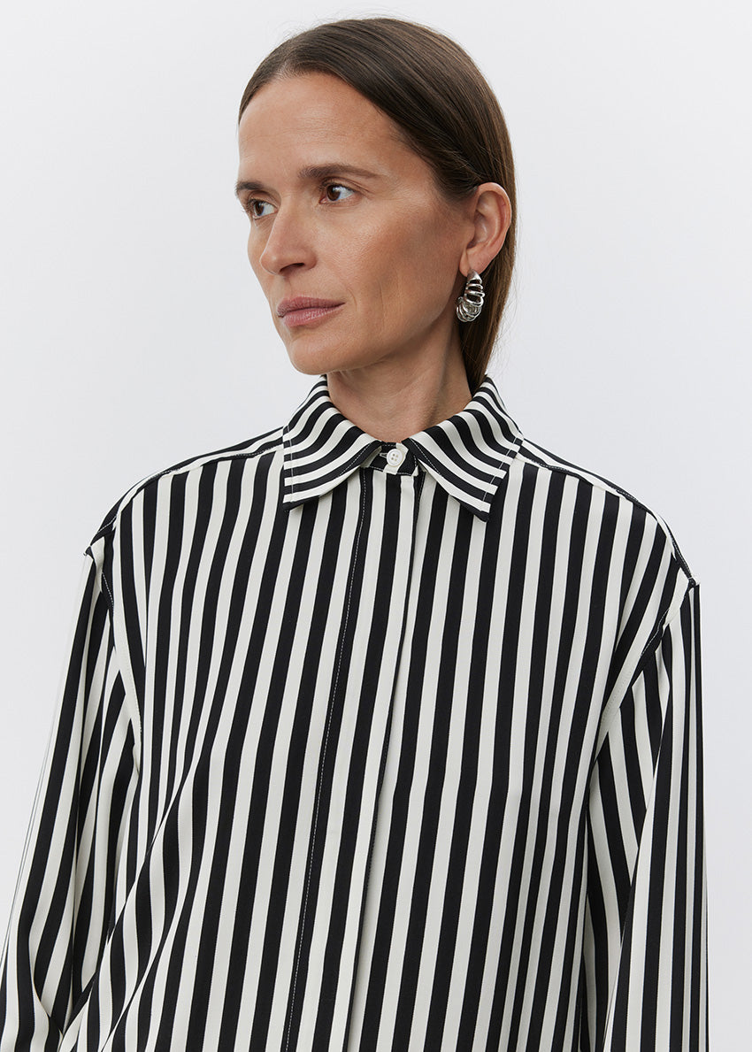 Woman wearing a black and white striped shirt against a plain background